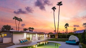 Una casa moderna con piscina, poltrona relax e una tenda.