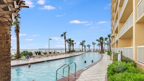 Una piscina con vista al océano, rodeada de palmeras y sillas de descanso.