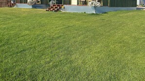 Um edifício grande e verde, com varanda coberta e um pequeno jardim na frente.