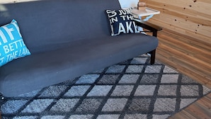 L’intérieur chaleureux d’un chalet avec un mur en bois, un canapé, un tapis et un tableau représentant une jetée.