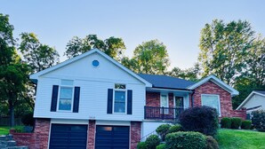 A two-story house with a garage, a balcony, and a well-maintained lawn.