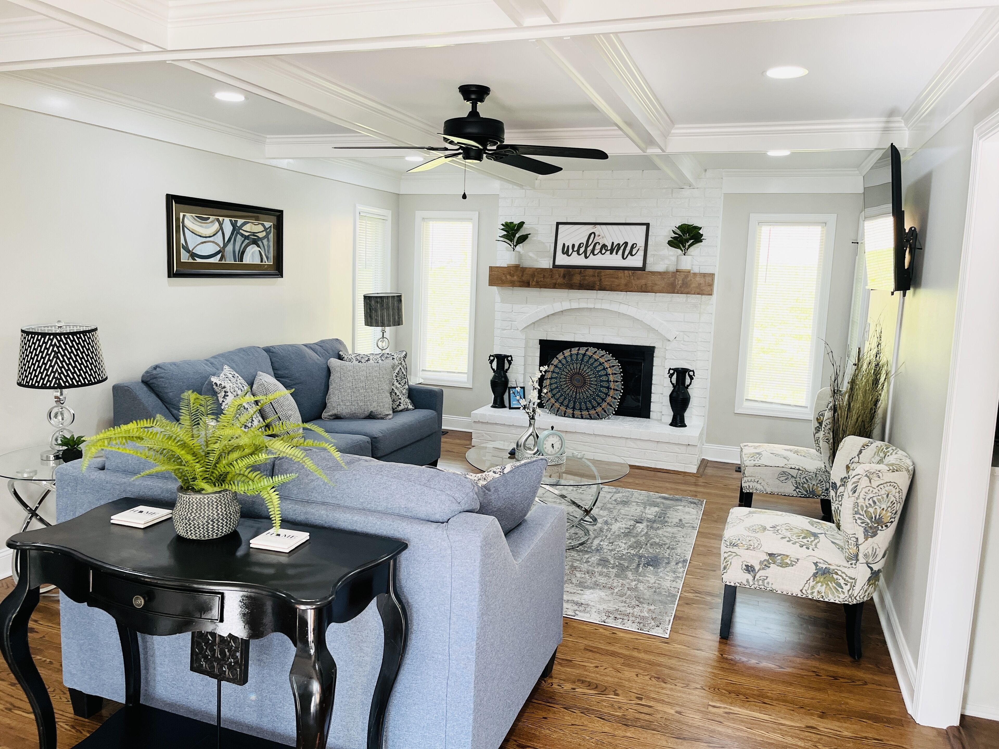 A living room with a fireplace, a ceiling fan, and a sofa.