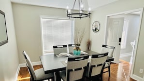 A dining room with a dark wooden table, four chairs, a vase, and a chandelier.