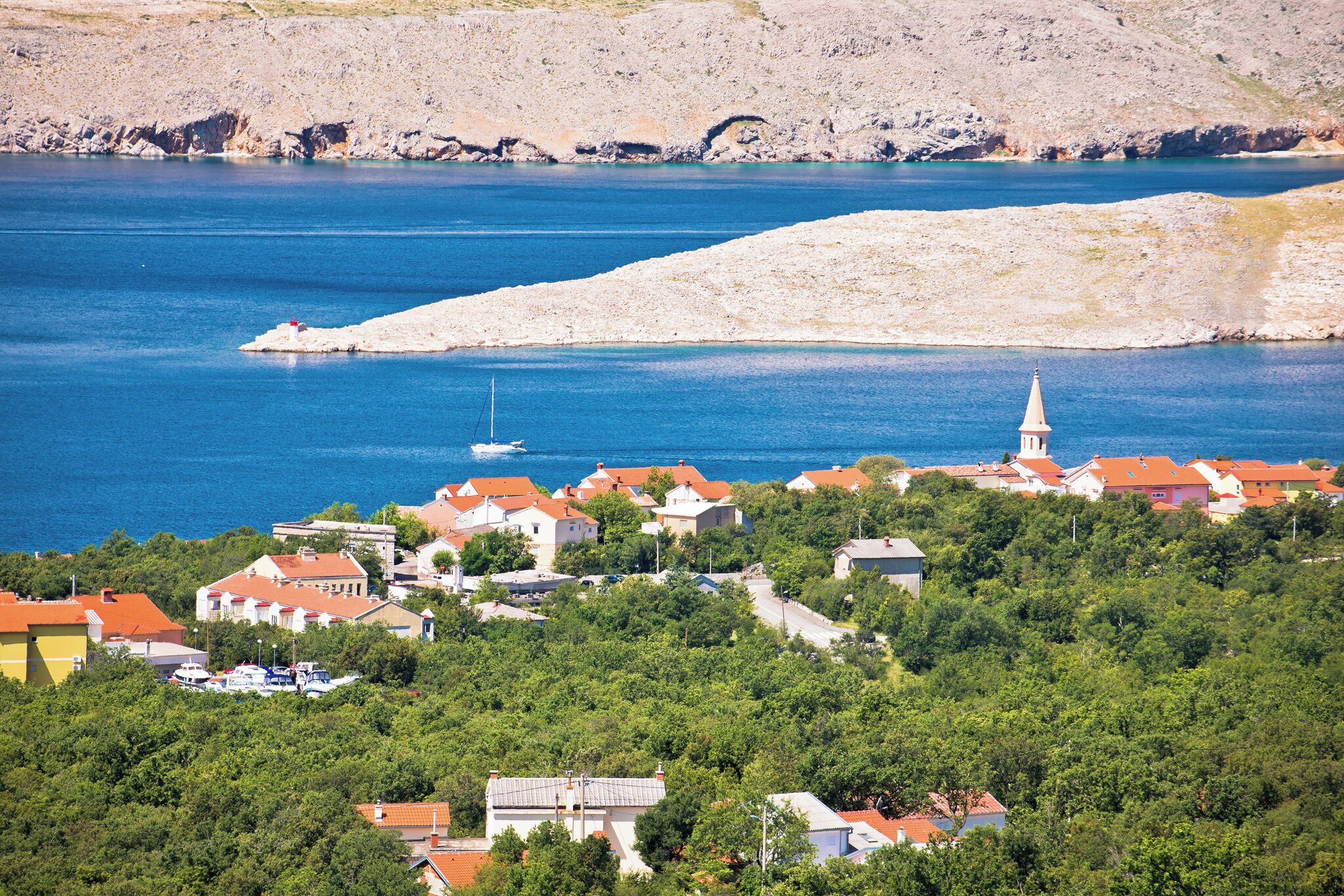 A coastal village with houses, a church, and a clear blue sea.