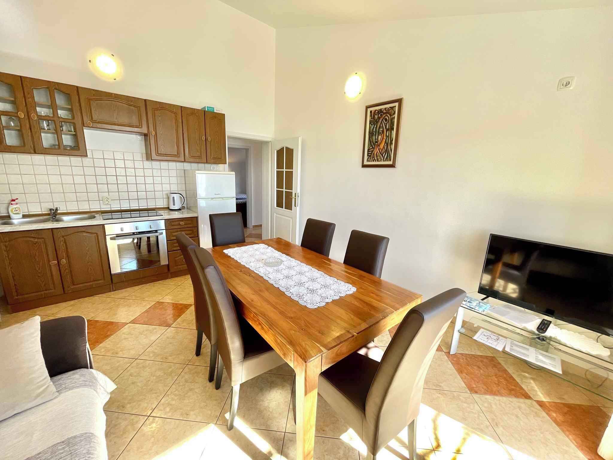 Una cucina moderna con mobili in legno, un tavolo da pranzo con sedie, una TV e un frigorifero.