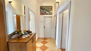 A hallway with a wooden cabinet, a mirror, and a painting on the wall. - Holiday apartment with balcony and sea view (Crikvenica)