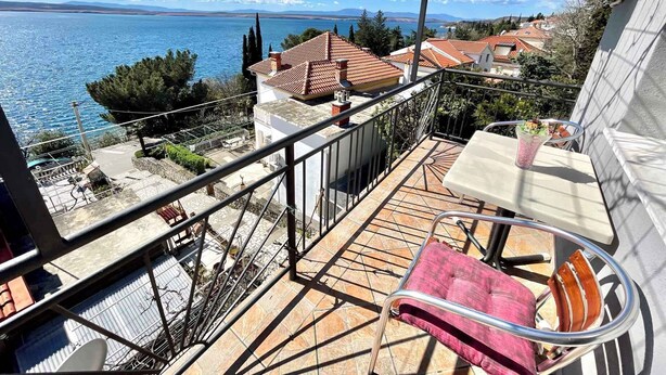 A balcony with a view of a lake, a table, and a chair. - Holiday apartment with balcony and sea view (Crikvenica)