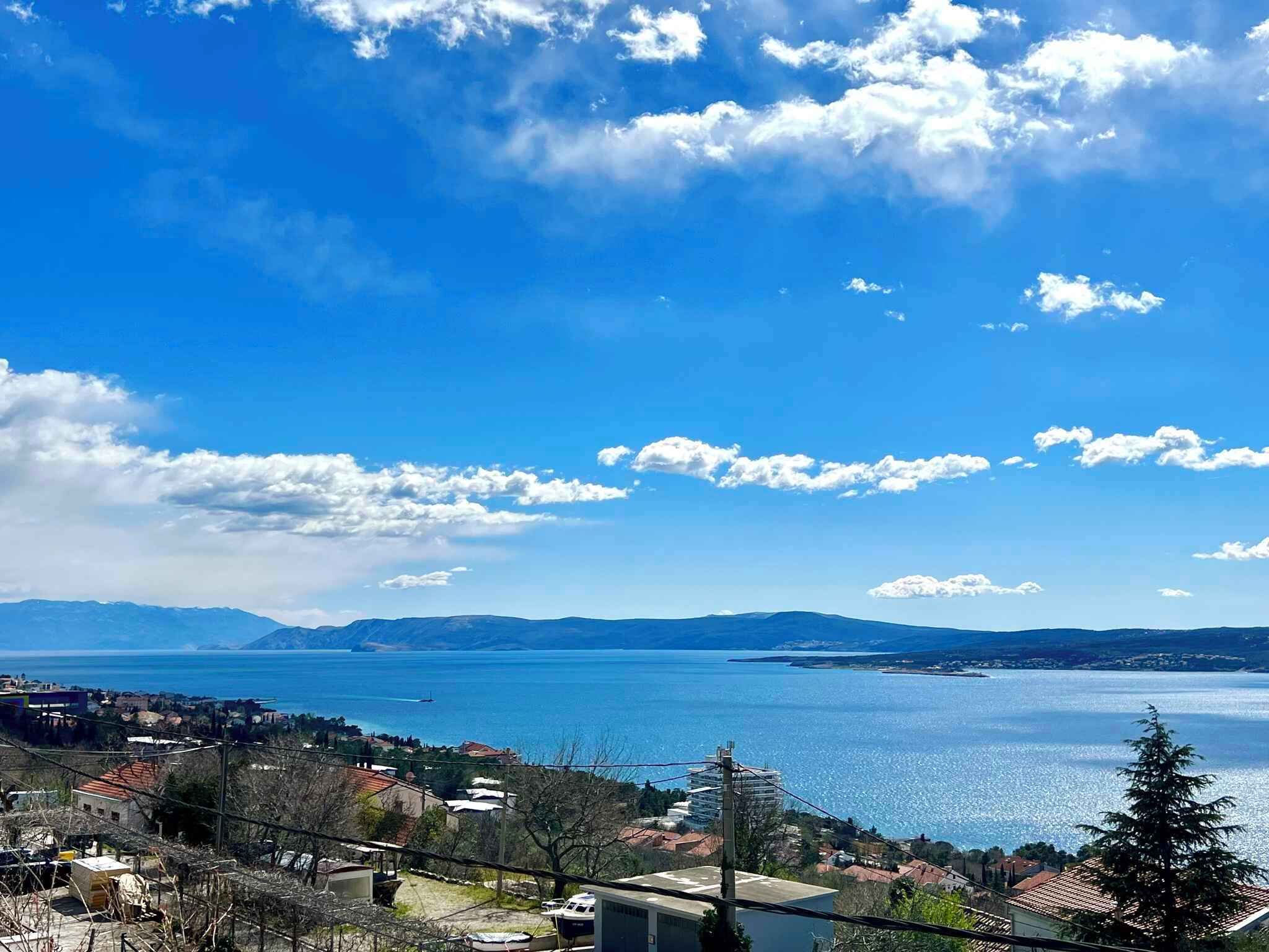 A coastal town with a view of the sea and mountains in the distance.