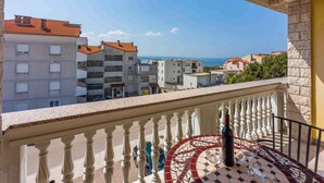 Un balcone con pavimento decorato, una bottiglia di vino e vista sul mare e sugli edifici.