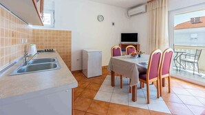 Una cucina compatta con lavandino, piccolo frigorifero e zona pranzo con tavolo e sedie.