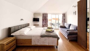 Une chambre à coucher avec un lit, une table de chevet en bois, une télévision, un canapé et une porte coulissante.
