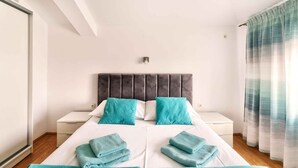 A modern hotel room with a large bed, two nightstands, a wardrobe, and a window with curtains. - Holiday apartment with two bedrooms (Crikvenica)