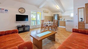 A spacious living room with a TV, a wooden table, and orange sofas. - Holiday apartment with two bedrooms (Crikvenica)