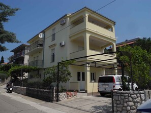 Un edificio residenziale a più piani con balconi, un muro in pietra e un furgone parcheggiato.