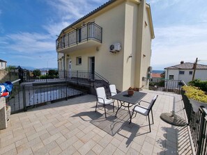 Un edificio con un balcone, posti a sedere all'aperto e vista sul mare.