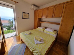 A bedroom with a bed, wooden wardrobe, and a balcony with a view.