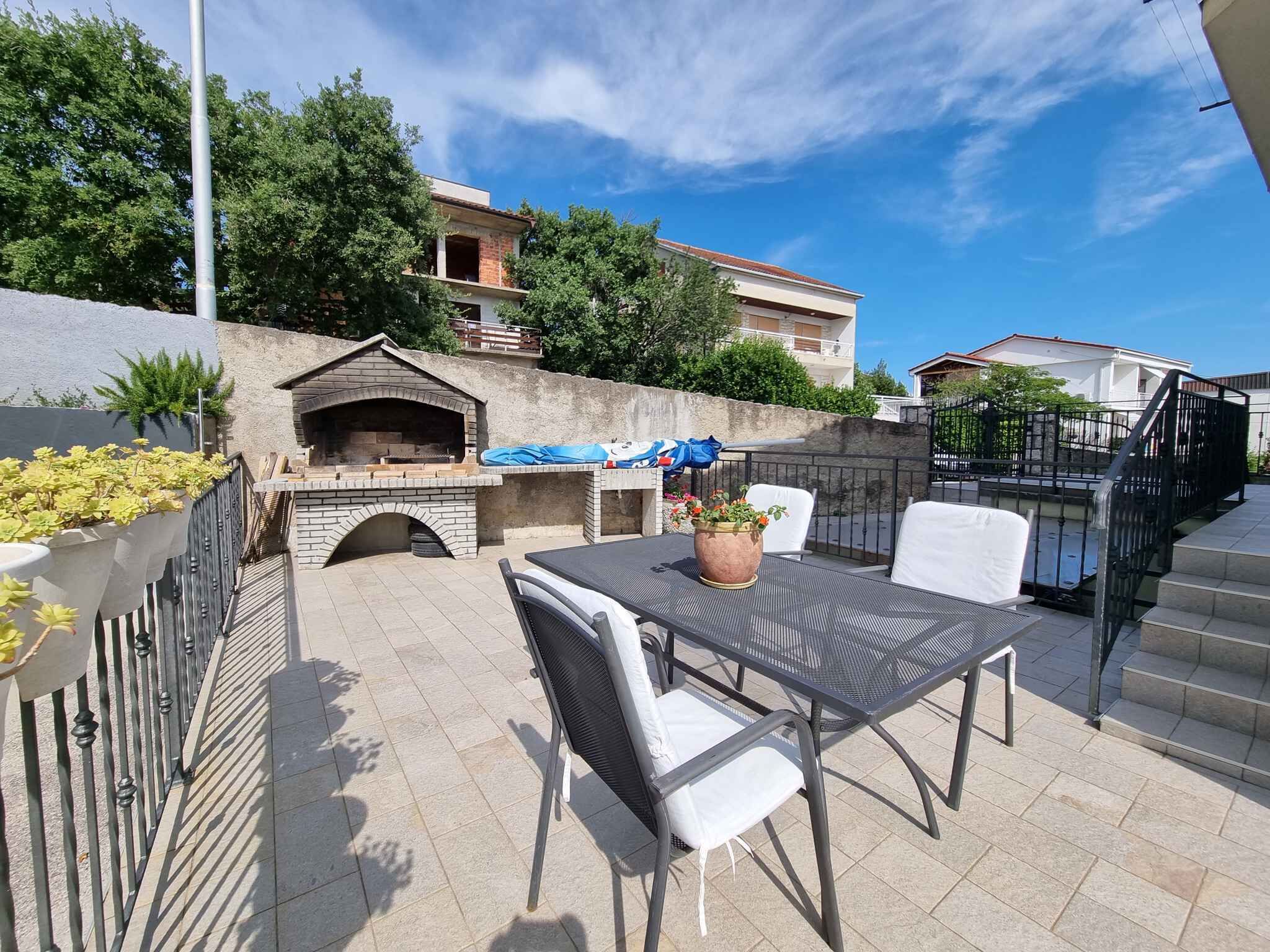 Une terrasse extérieure équipée d’un barbecue, de sièges et offrant une vue sur le quartier.