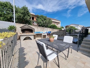 An outdoor patio with a barbecue grill, seating, and a view of the neighborhood.