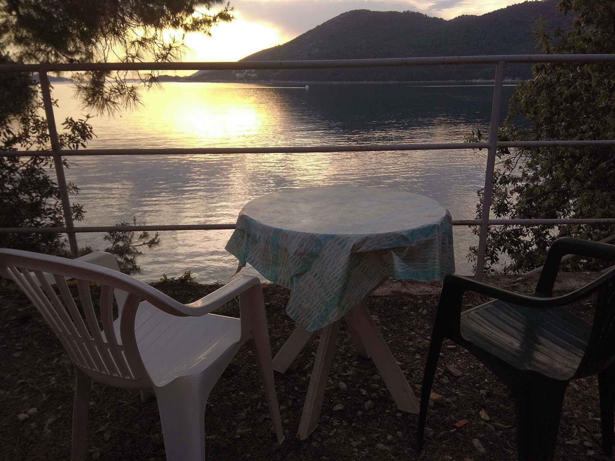 Ein Tisch und zwei Stühle vor einem Blick auf See und Berge.