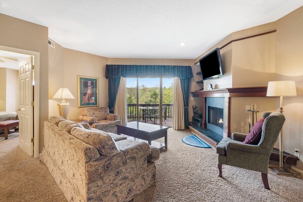 A living room with a sofa, armchair, and coffee table, a fireplace, and a television.