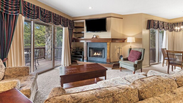 A living room with a fireplace, a television, and a view of the outdoors. - StoneBridge Village Villa - Located Minutes from Silver Dollar City (Reeds Spring)
