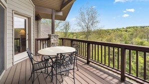 Une terrasse en bois avec une table ronde et des chaises, donnant sur une zone boisée.