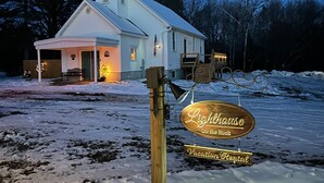 Un bâtiment blanc doté d’un porche et d’une enseigne sur laquelle on peut lire : « Location de vacances – Le Phare sur le Rocher ».