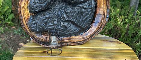 A wooden sculpture of a bear in a tree hollow, placed on a wooden table outdoors.