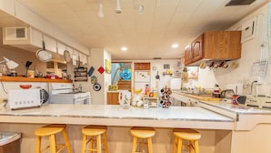 Une cuisine dotée d’un grand îlot central, de tabourets en bois et de divers appareils électroménagers.