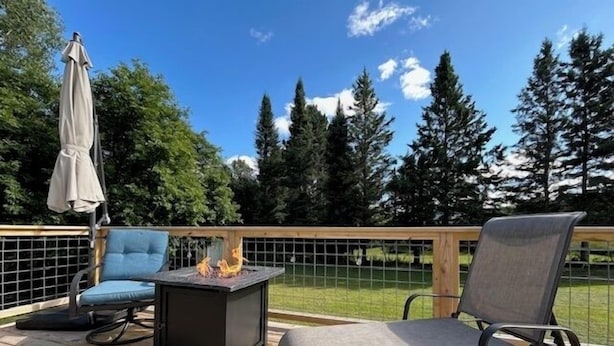 Une terrasse en bois avec deux chaises, une petite table et un foyer.