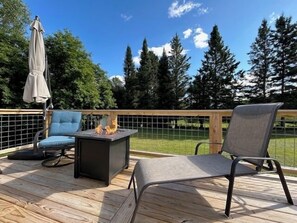 Une terrasse en bois avec deux chaises, une petite table et un foyer.
