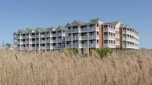 A multi-story hotel with balconies and a beach view. - C103A- Sweet Sound Memories, Soundfront Nags Head | Sunset Views & Pool (Nags Head)