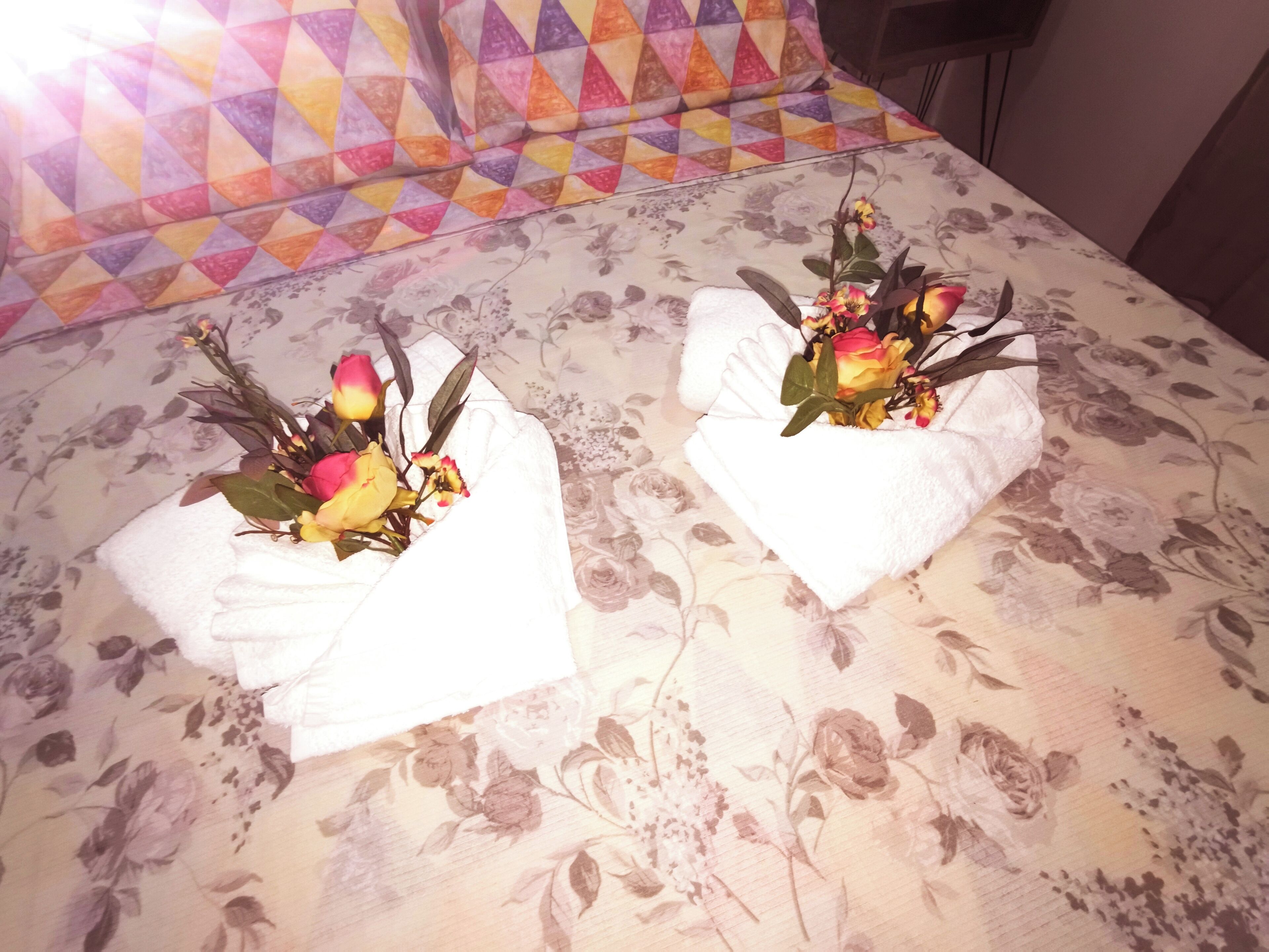 Ein Bett mit blumigem Bettzeug und zwei Handtücher mit floralen Mustern.