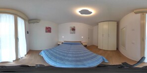 Ein Schlafzimmer mit Bett, Kleiderschrank, Nachttisch, Wandairconditioner und einem fenster mit Vorhängen.