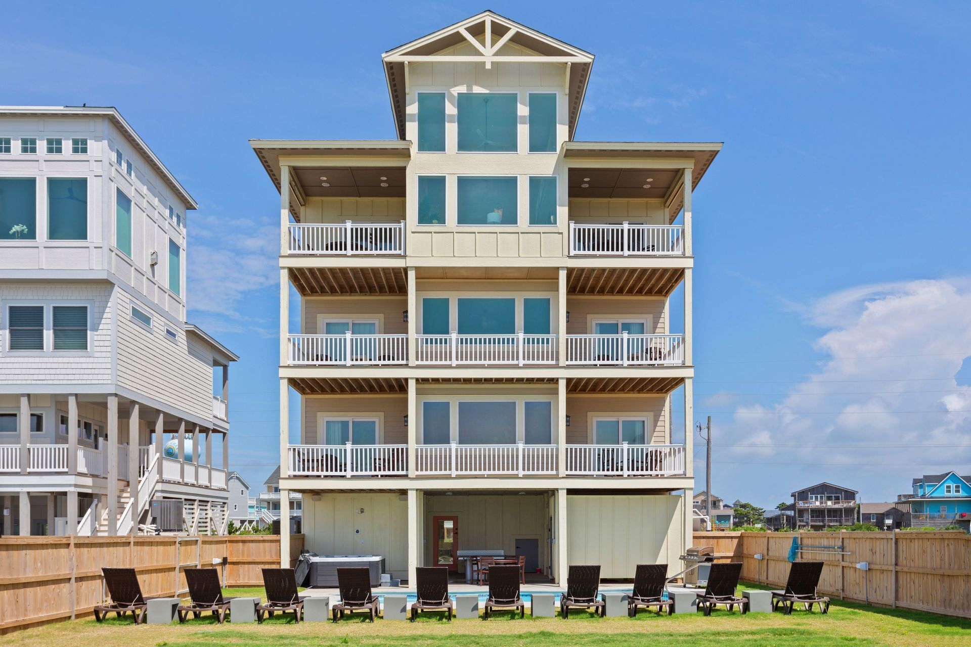 A multi-story beachfront building with balconies, a pool area, and outdoor seating.