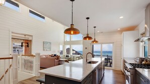 A spacious kitchen with a large island, wooden flooring, and a view of the ocean.