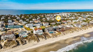 An aerial view of a coastal residential area with houses, a beach access sign, and a large body of water. - Fore Decs: Private Pool, Tiki Bar & Ocean Views (Corolla)