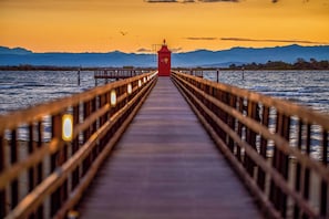 Une jetée menant à un phare, d’où l’on peut admirer des montagnes au loin.