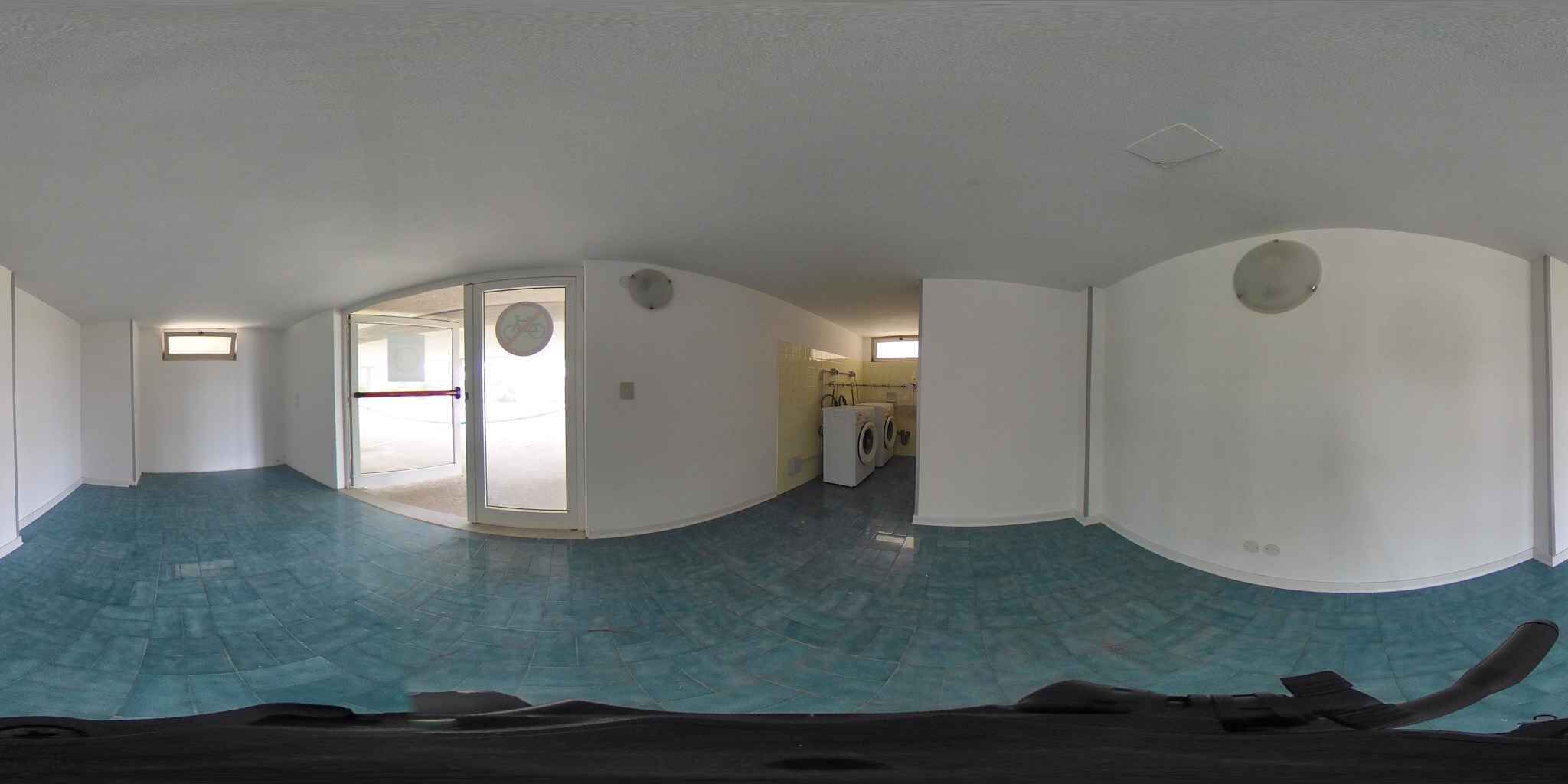 A panoramic view of a room with a curved ceiling, a washing machine, and a door leading to another room.