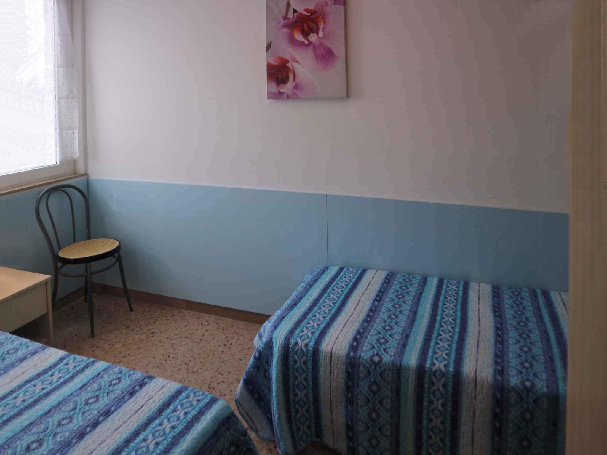 A room with two beds, a chair, a small table, and a window.