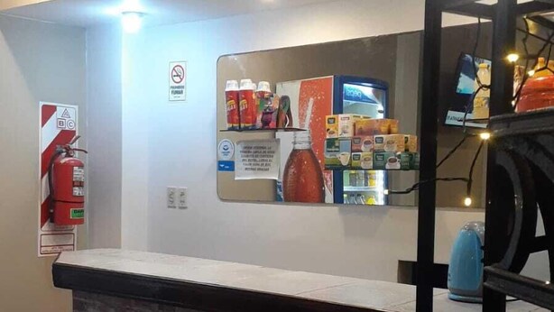 Un mostrador de recepción con encimera de ladrillo, un extintor y un cartel de prohibido fumar.
