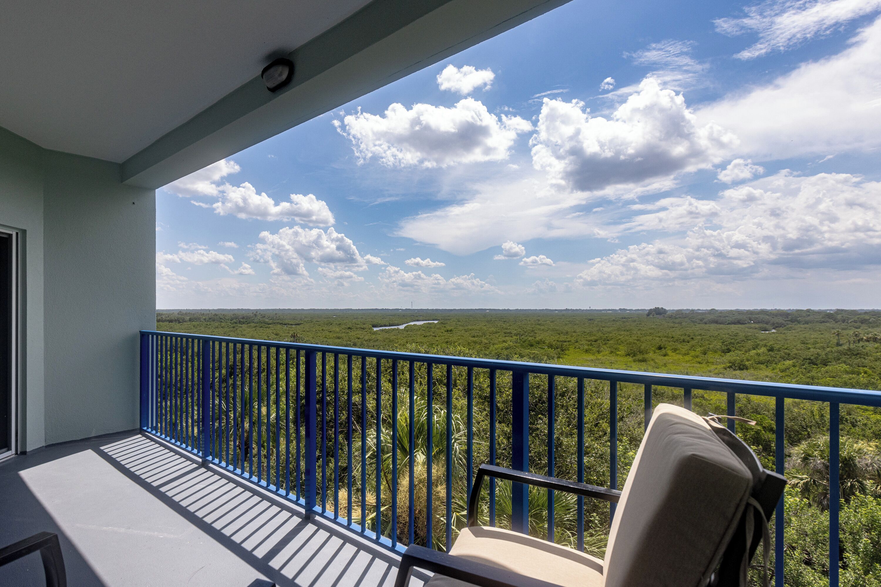 Een balkon met een blauwe balustrade met uitzicht op een weelderig landschap.