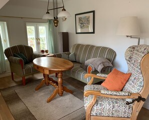 Uma sala de estar aconchegante com um sofá listrado, uma mesa de centro de madeira e duas poltronas.