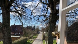 A residential street with houses on both sides, a white picket fence, and trees framing the view. - Ferienwohnung Apfelrose - Urlaub im Malerischen Inseldorf Oldsum (Oldsum)