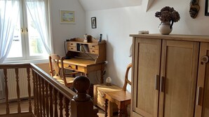 A room with a wooden desk, a cabinet, a chair, and a staircase. - Ferienwohnung Apfelrose - Urlaub im Malerischen Inseldorf Oldsum (Oldsum)