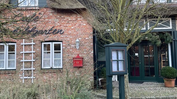 A traditional brick building with a thatched roof, a sign reading "The Blacksmith," and a stone wall in the foreground. - Ferienwohnung Apfelrose - Urlaub im Malerischen Inseldorf Oldsum (Oldsum)