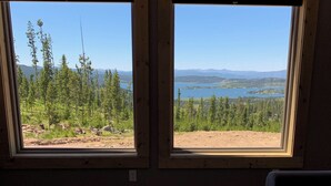 Une pièce dotée de deux grandes fenêtres donnant sur une forêt et un lac.