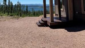 Une cabane en bois dotée d’un porche couvert et offrant une vue sur un lac et des montagnes.
