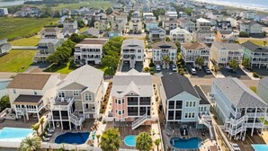 A residential area with multiple houses, a swimming pool, and a view of the beach. - Carlton by Brunswick Vacation Rentals: Private Pool, Elevator, and Beach Access (Supply)