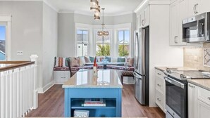 A modern kitchen with a central island, stainless steel appliances, and a seating area with a view. - Carlton by Brunswick Vacation Rentals: Private Pool, Elevator, and Beach Access (Supply)